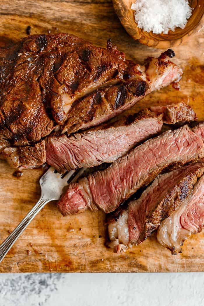 Overhead shot of Chipotle Steak Au Poivre being cut after resting on a wooden cutting board 