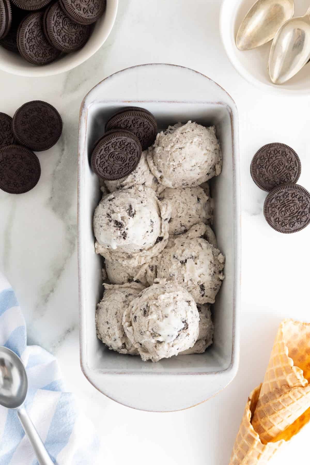 A loaf pan filled with scoops of cookies and cream ice cream and Oreo cookies nestled throughout