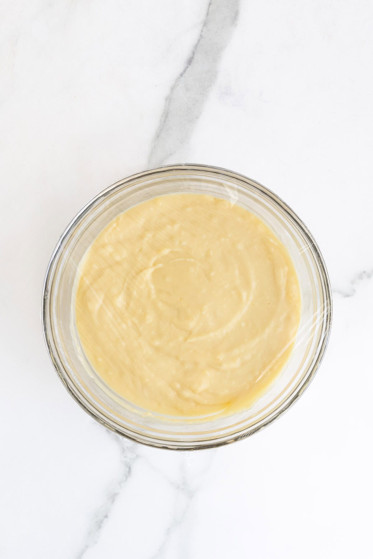 Custard in a glass bowl covered with plastic wrap