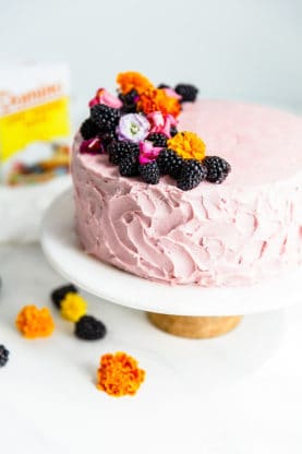 Homemade Chocolate Cake Recipe topped with a blackberry buttercream and fresh blackberries and flowers.