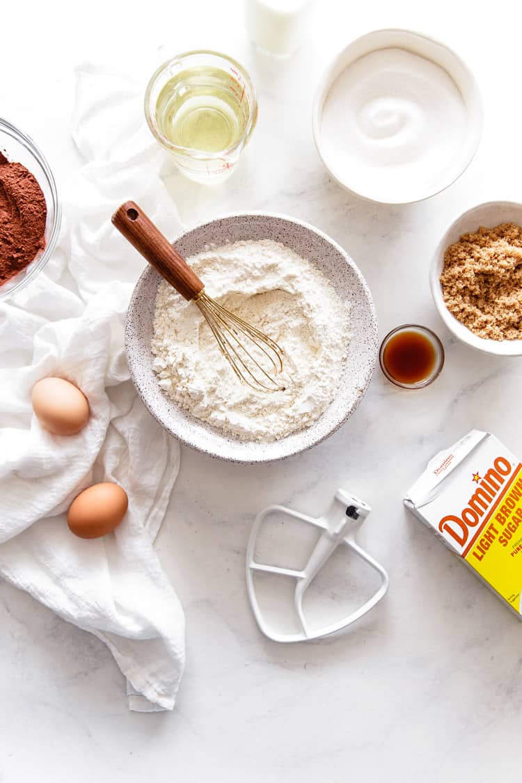 Overhead shot of ingredients used to make the best chocolate cake recipe with blackberry buttercream including a box of Domino sugar, flour, and eggs