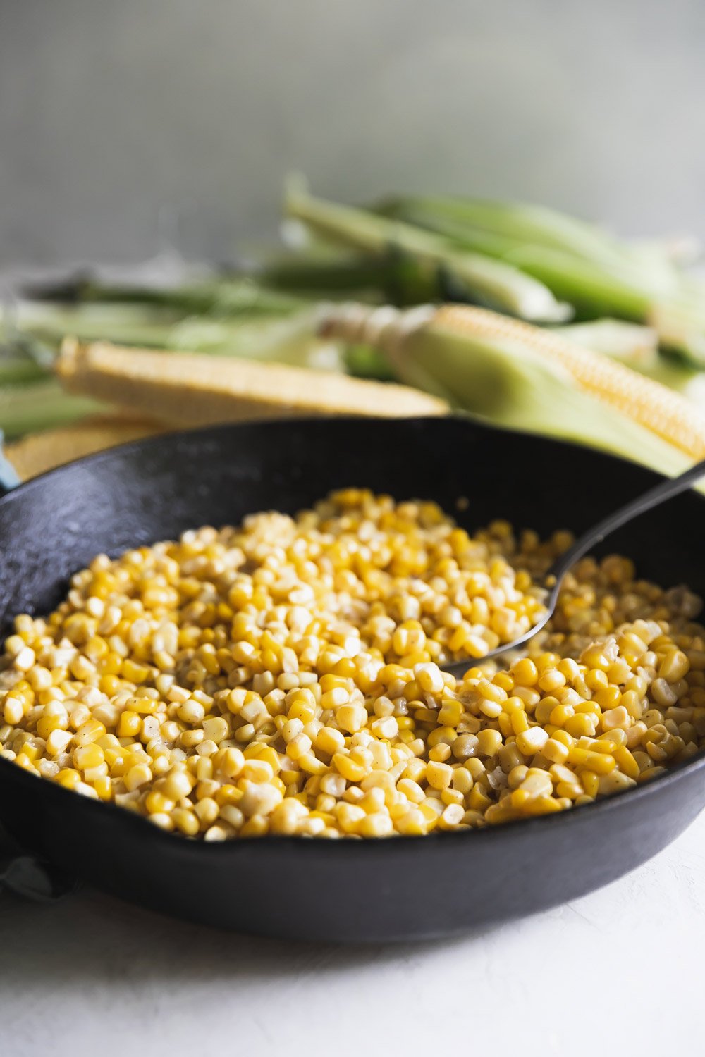 Close up of fried corn in a black cast iron skillet with a spoon in it