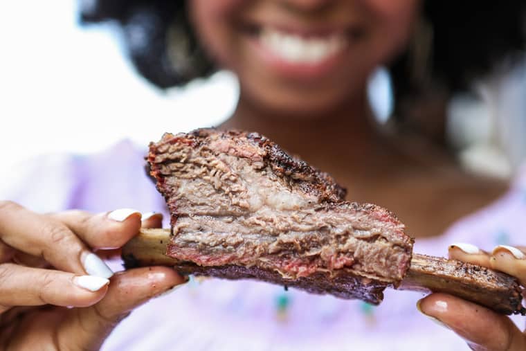 Jocelyn holding one tender, juicy, and flavorful beef rib completely cooked and delicious