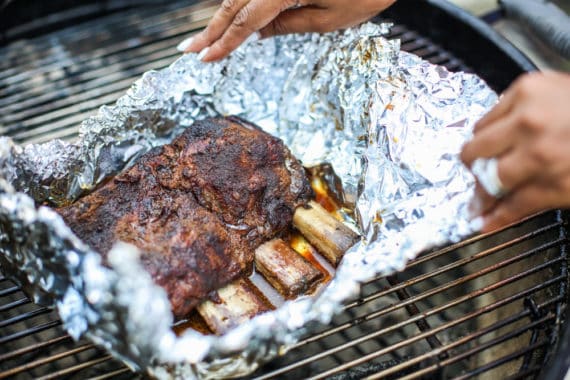 Beef ribs wrapped in aluminum foil over a BBQ grill