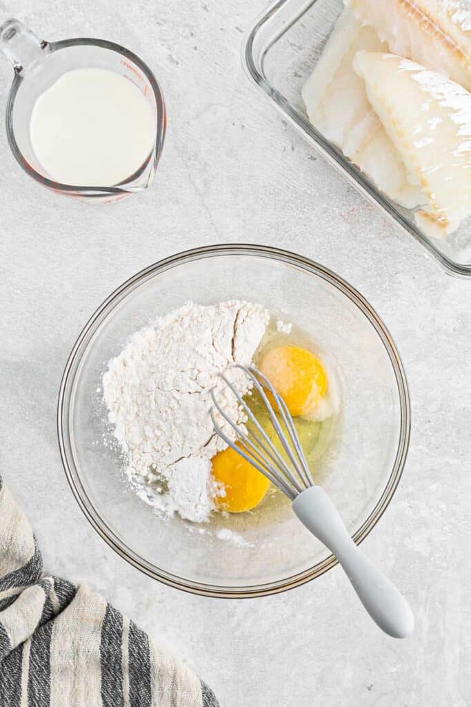 The flour and egg in a mixing bowl with a whisk.