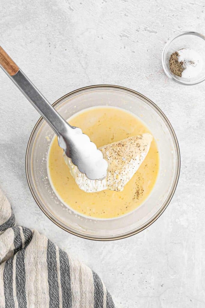Dipping the fish into the batter with tongs.