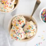 Overhead shot of two bowls filled with scoops of homemade vanilla ice cream topped with rainbow sprinkles
