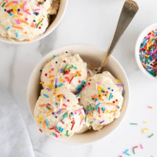 Overhead shot of two bowls filled with scoops of homemade vanilla ice cream topped with rainbow sprinkles