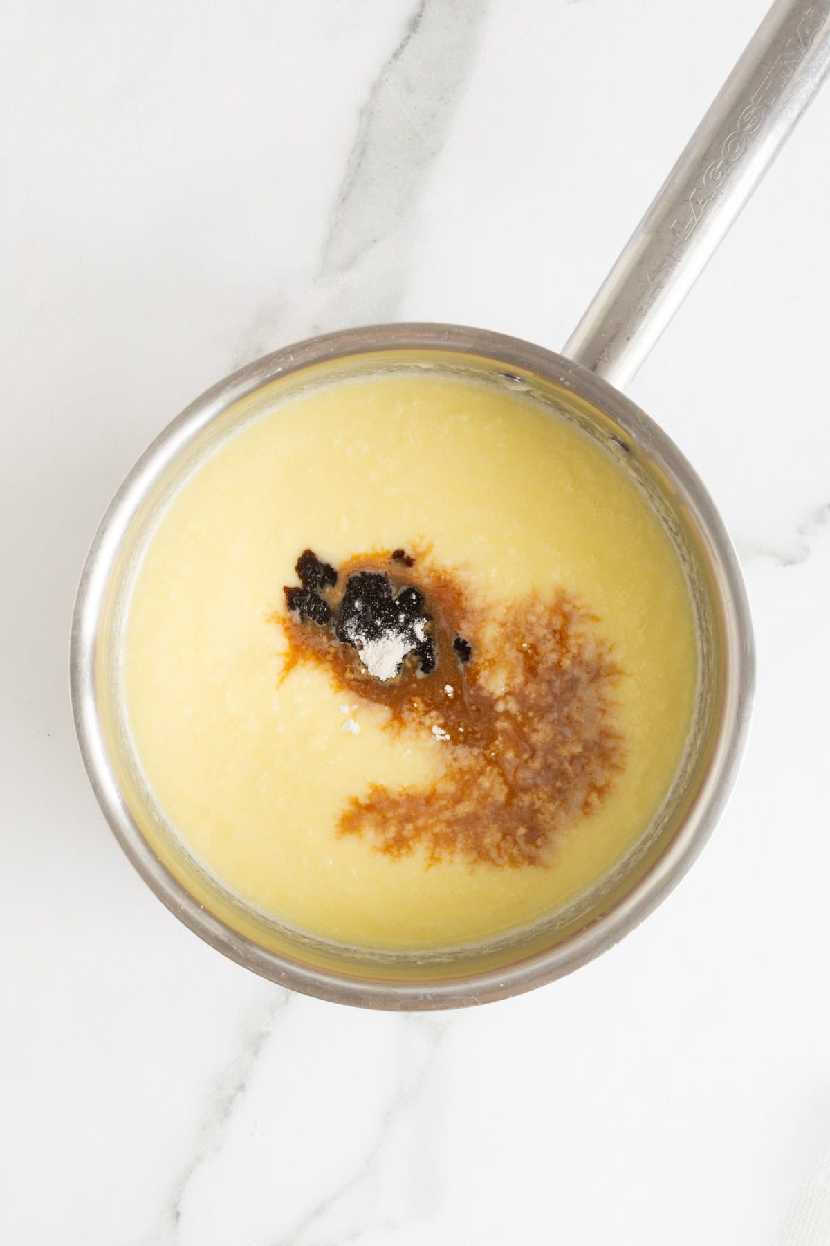 Vanilla and flour being added to the custard mixture in a saucepan