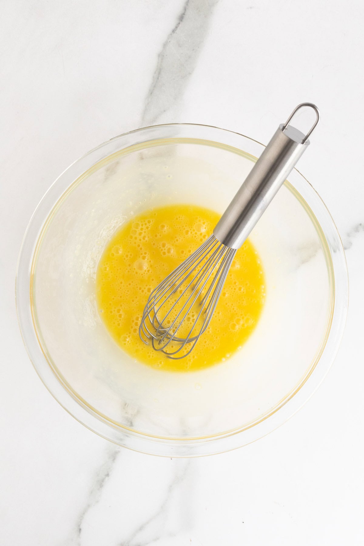Egg yolks whisked until smooth in a bowl with a metal whisk