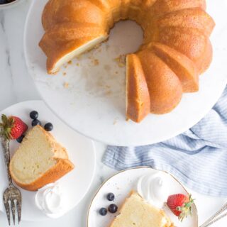 Sour cream pound cake on a white pedestal with slices cut on plates.