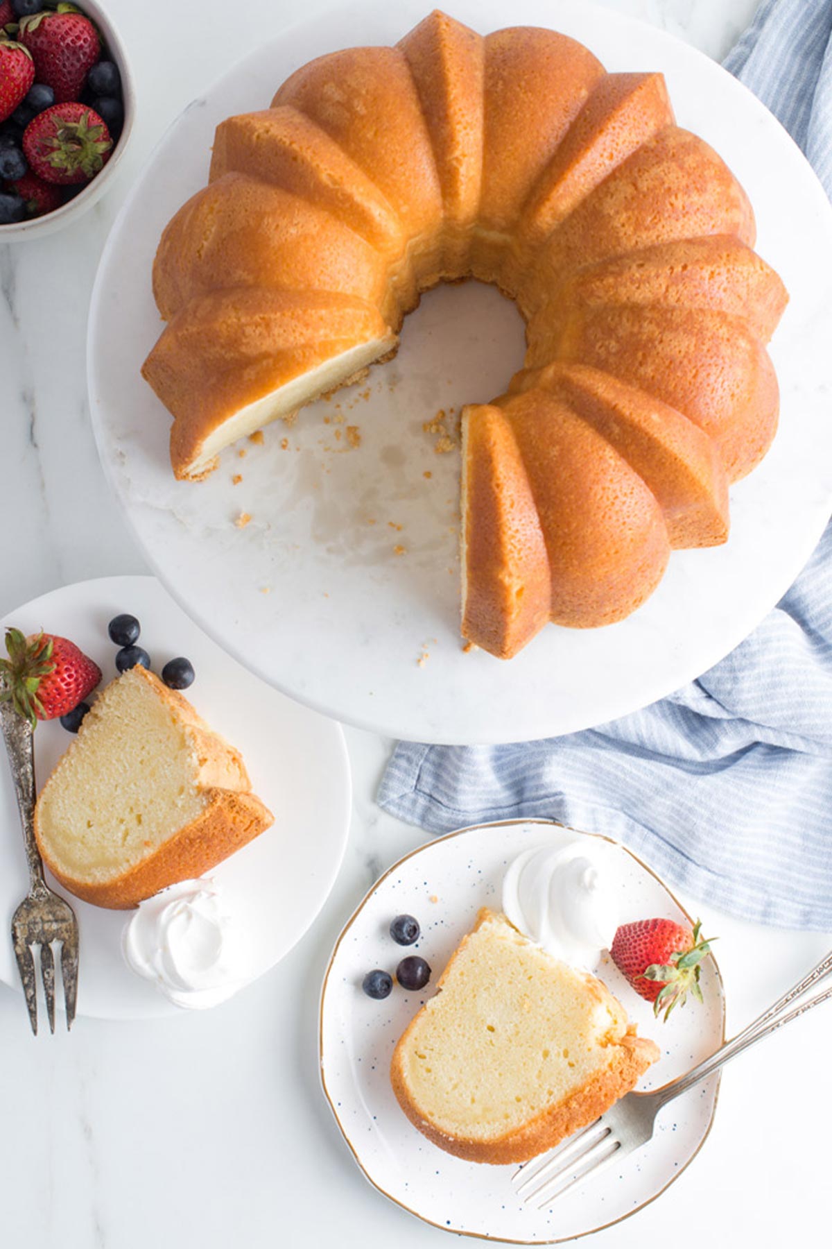 Sour cream pound cake on a white pedestal with slices cut on plates.