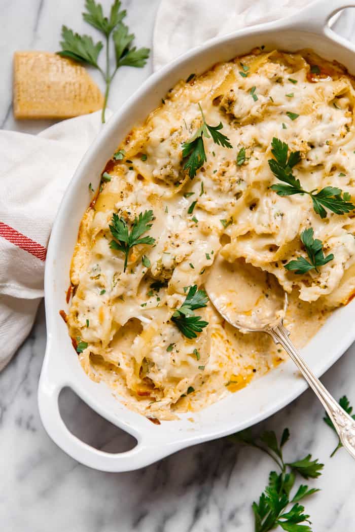 Flavorful chicken and broccoli are stuffed inside of tender pasta shells and smothered with cheese and a decadent cajun cream sauce all served in a white casserole dish with a spoon in it