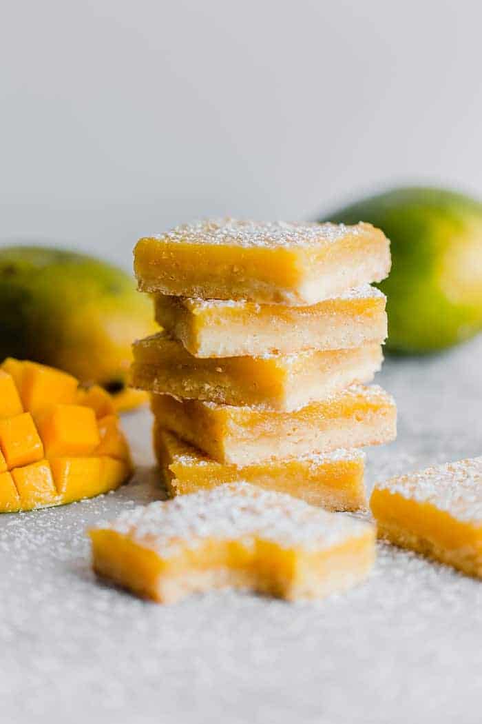 Lemon Bar Recipe stacked on top of each other with mango in the background.