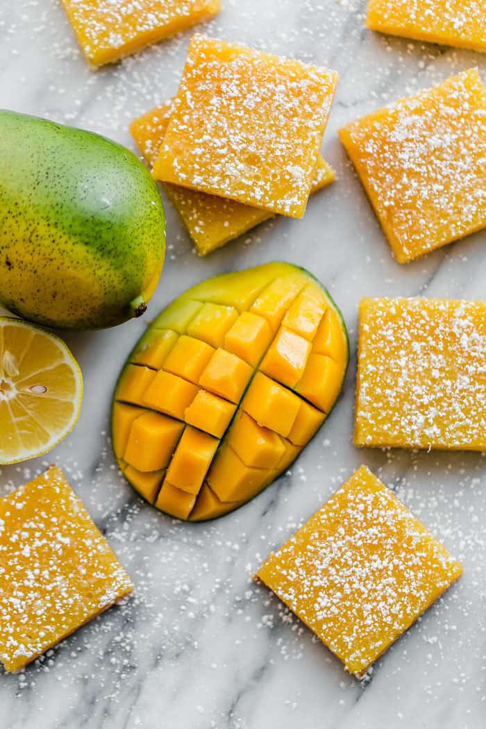 Overhead shot of several Mango Lemon Bars surrounded by a sliced mango