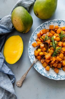 Roasted Butternut Squash Recipe with mango on blue and white plate with mangoes in background