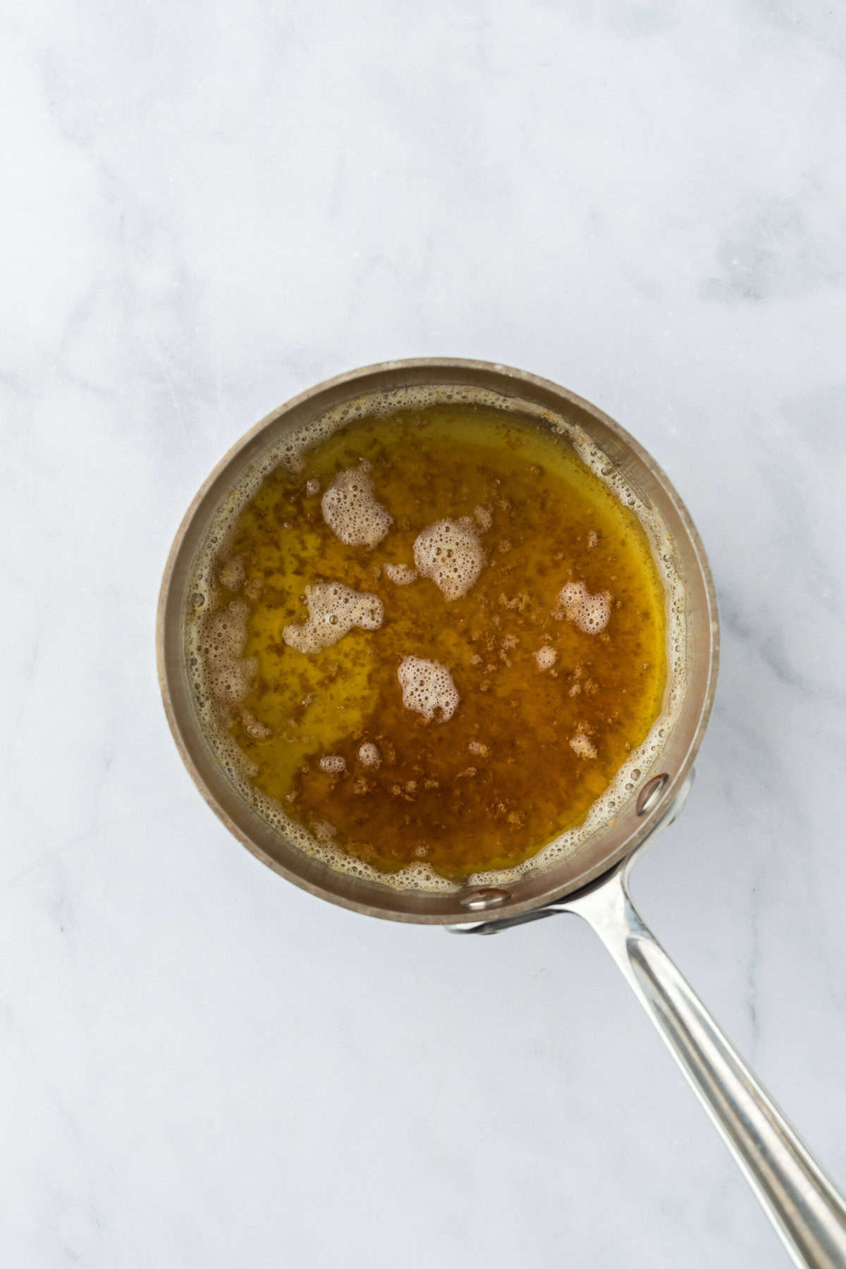 Browned butter in a saucepan on white countertop.