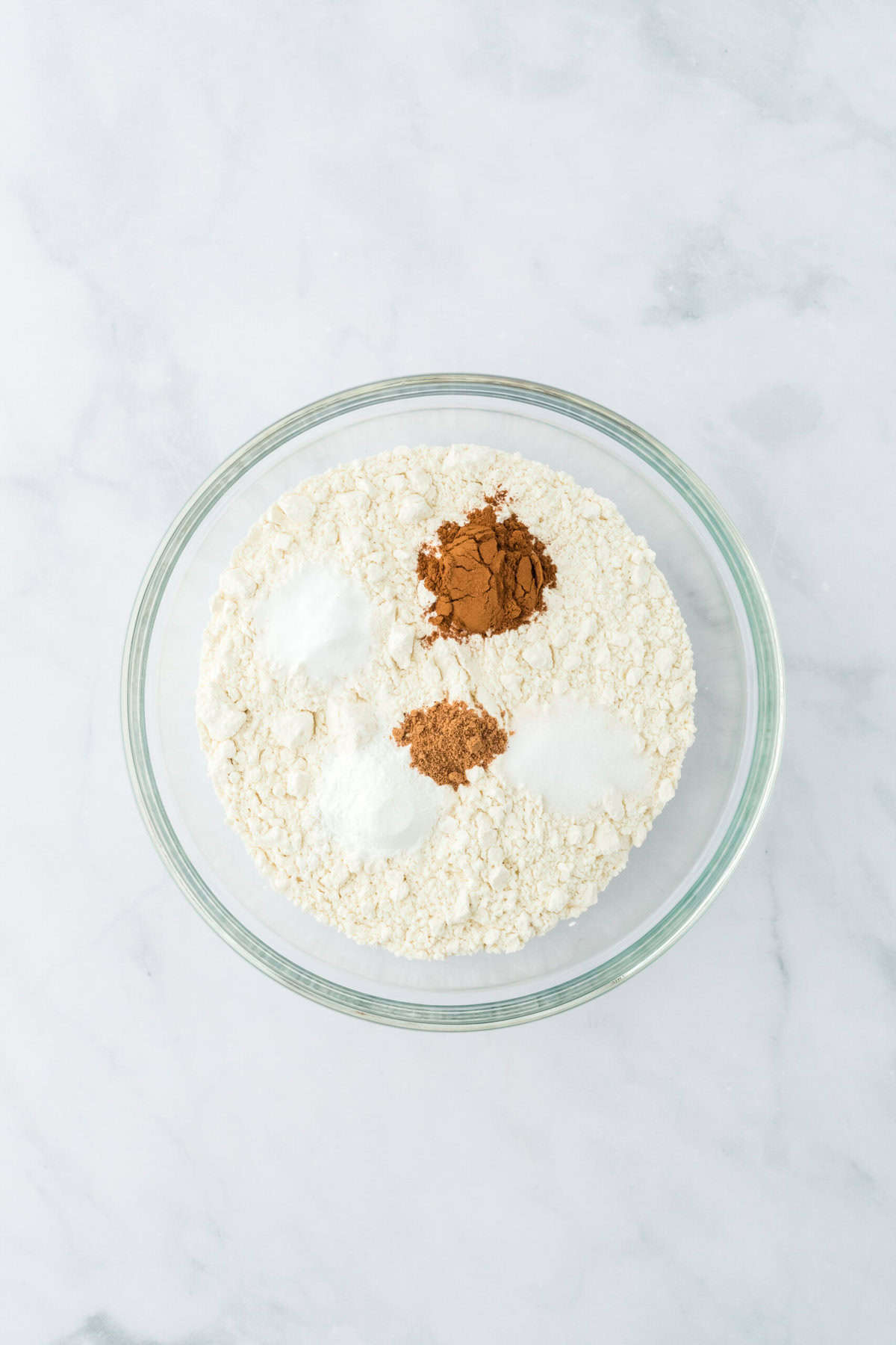 Spices and flour in a glass bowl on white countertop