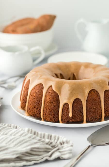 A large sweet potato pound cake recipe on a white plate with a white striped napkin with a white background