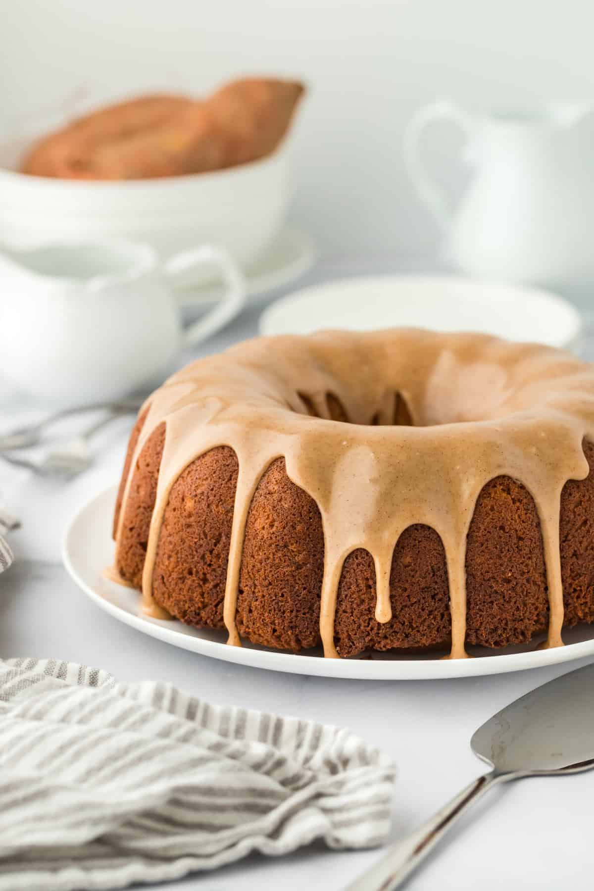 A large sweet potato pound cake recipe on a white plate with a white striped napkin with a white background