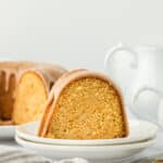 Gorgeous slice of sweet potato pound cake on two white plates with full cake in the white background ready to serve