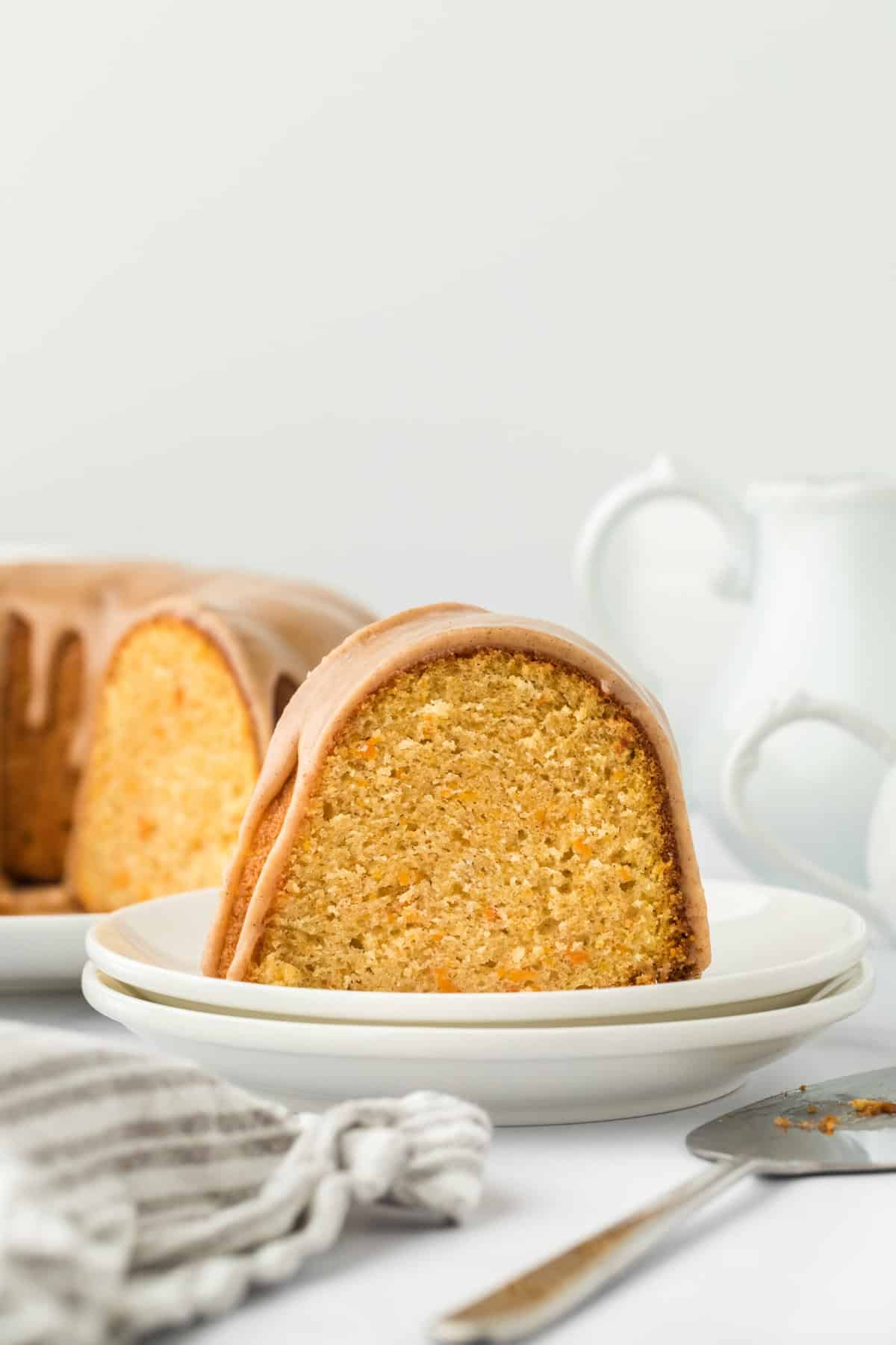 Gorgeous slice of sweet potato pound cake on two white plates with full cake in the white background ready to serve