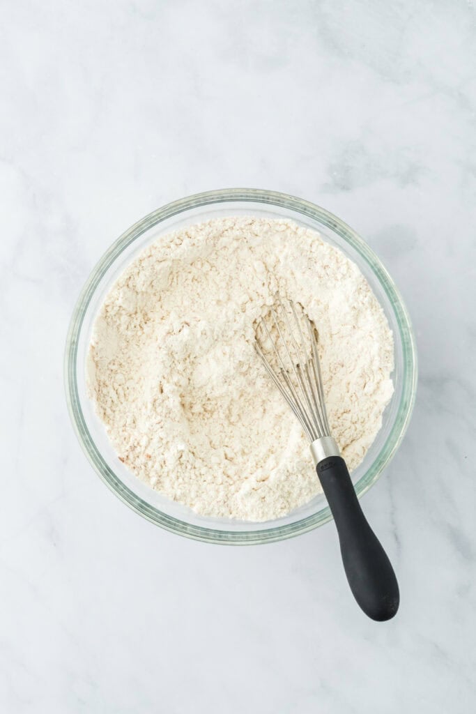 Dry ingredients whisked in a glass bowl on white countertop