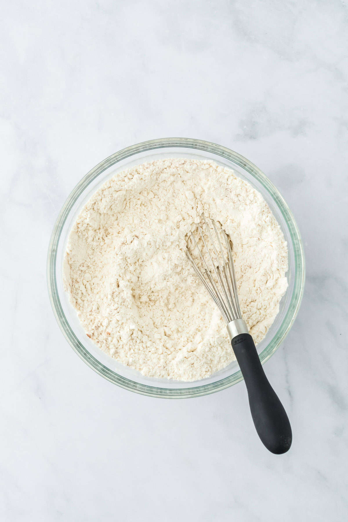 Dry ingredients whisked in a glass bowl on white countertop