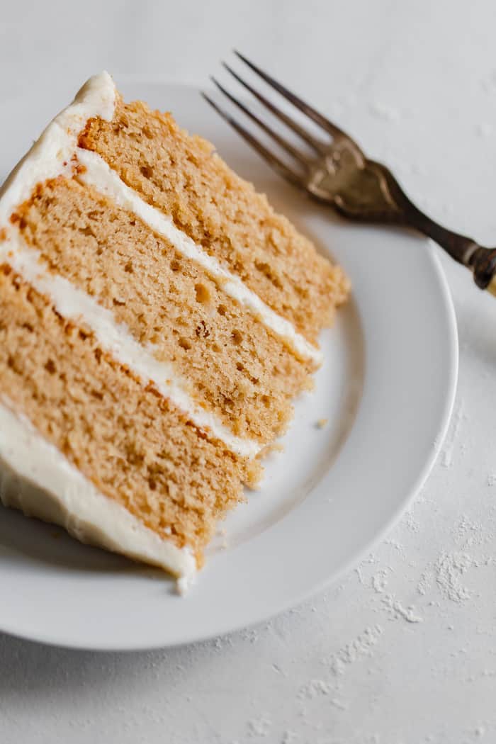 Close up of a giant slice of Easy Apple Cake Recipe with Brown Butter Frosting on white plate with fork