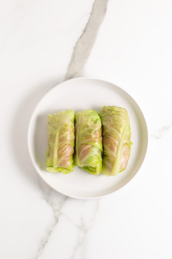 Wrapped cabbage leaves with meat mixture inside on white plate