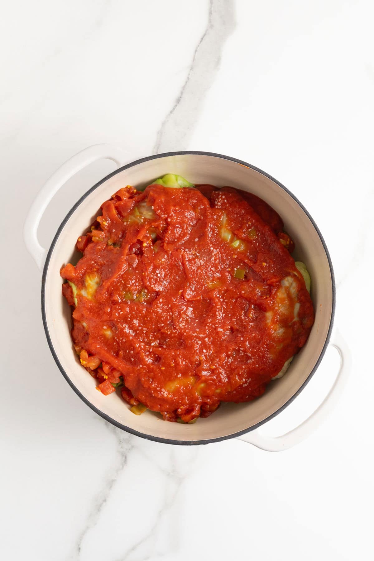 Tomato sauce on top of stuffed cabbage rolls in a large pot