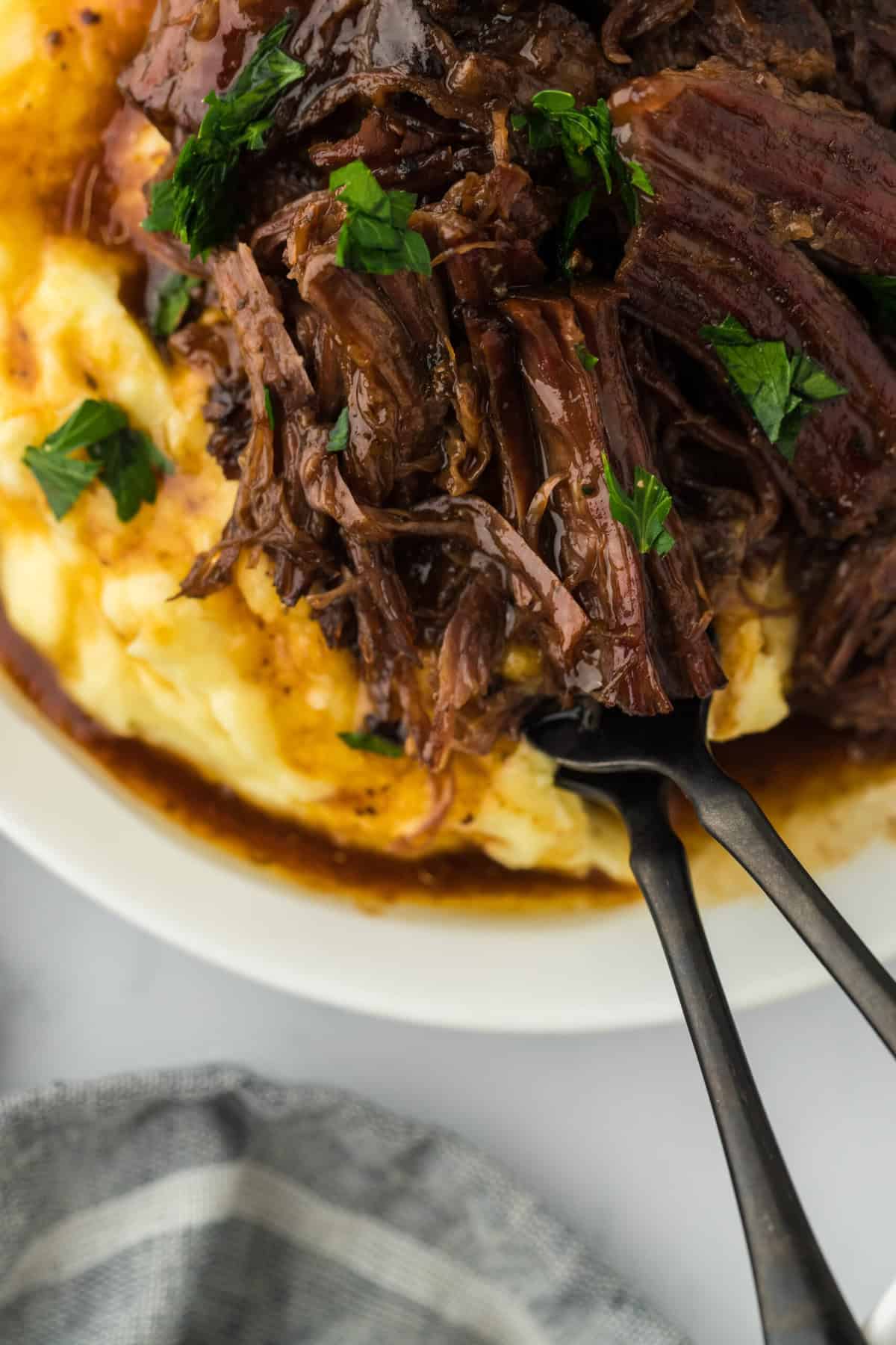 The best mississippi pot roast recipe served over mashed potatoes with two forks in a white plate