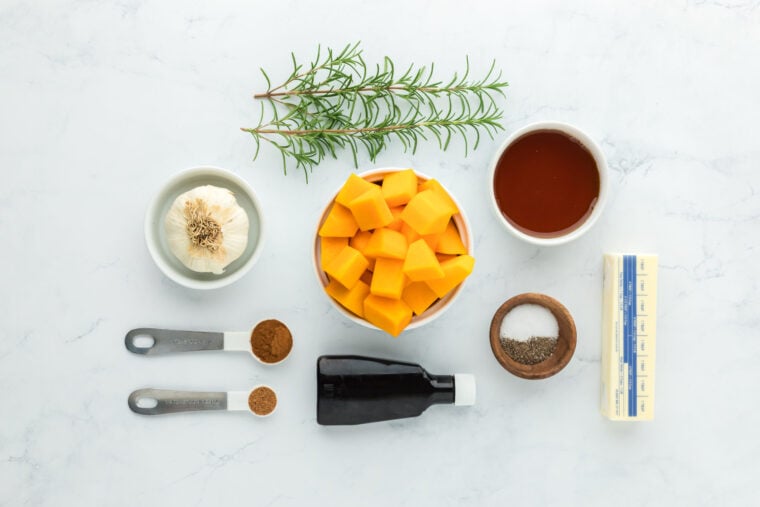 Butternut squash, vanilla, butter, garlic, spices and thyme on white countertop