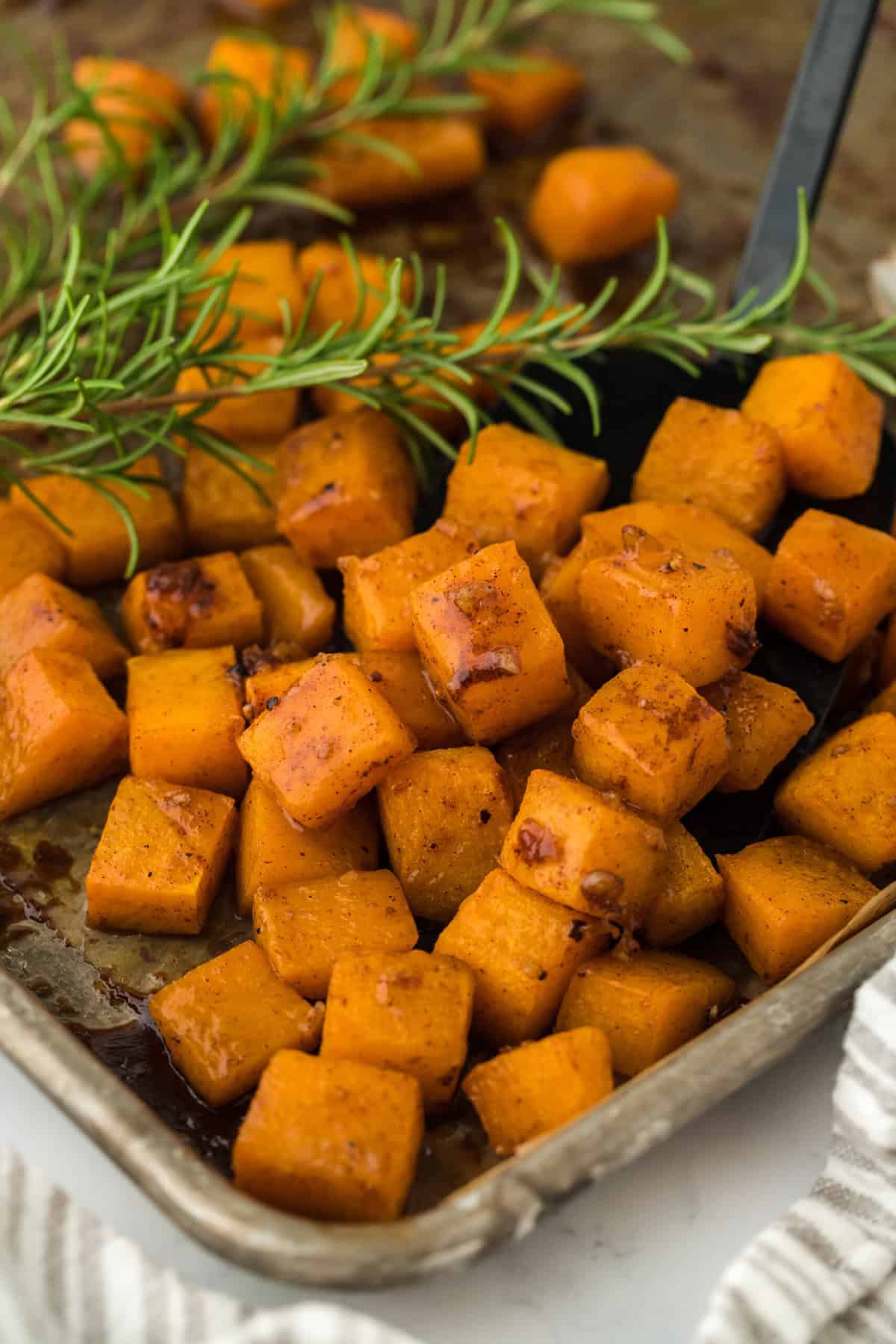 Roast butternut squash on a baking sheet pan on white countertop ready to serve