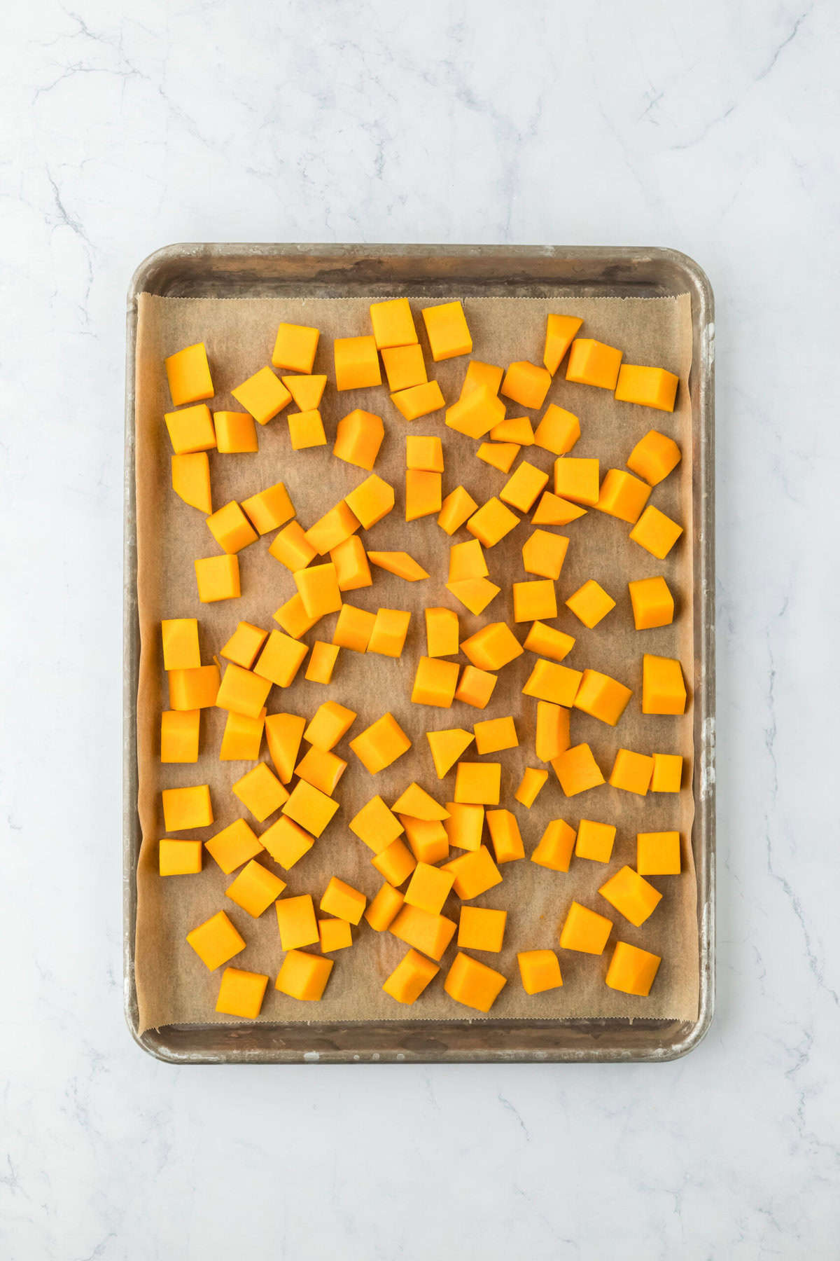 Cubed butternut squash on a baking sheet before baking