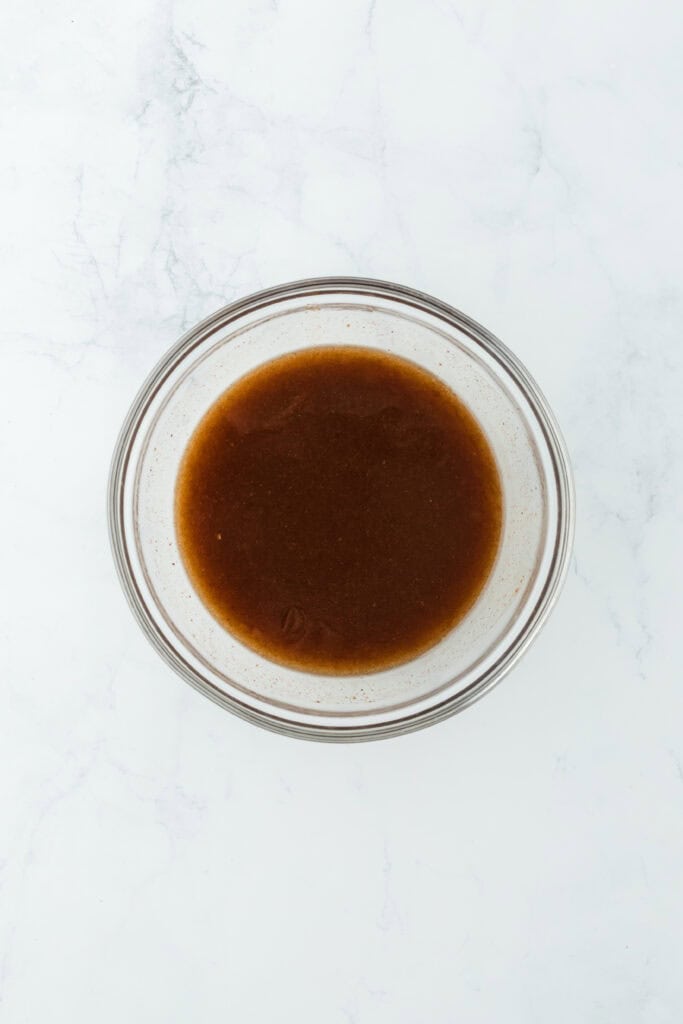 Whisked syrup mixture in glass bowl on white countertop
