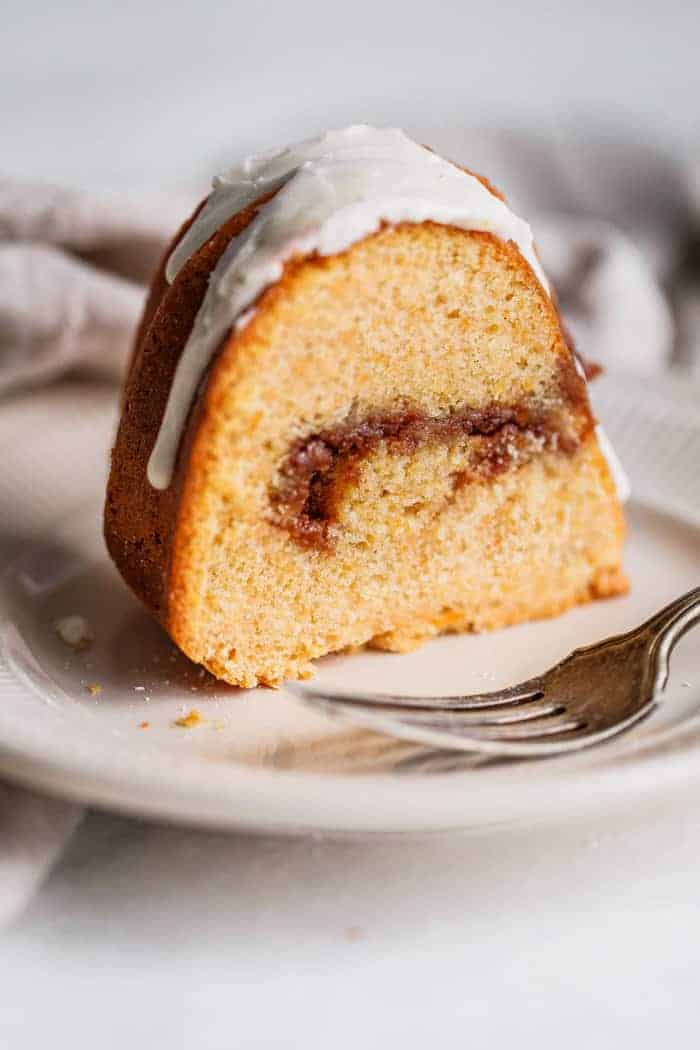 A slice of Sweet Potato Coffee Cake served on a white, round plate with a fork