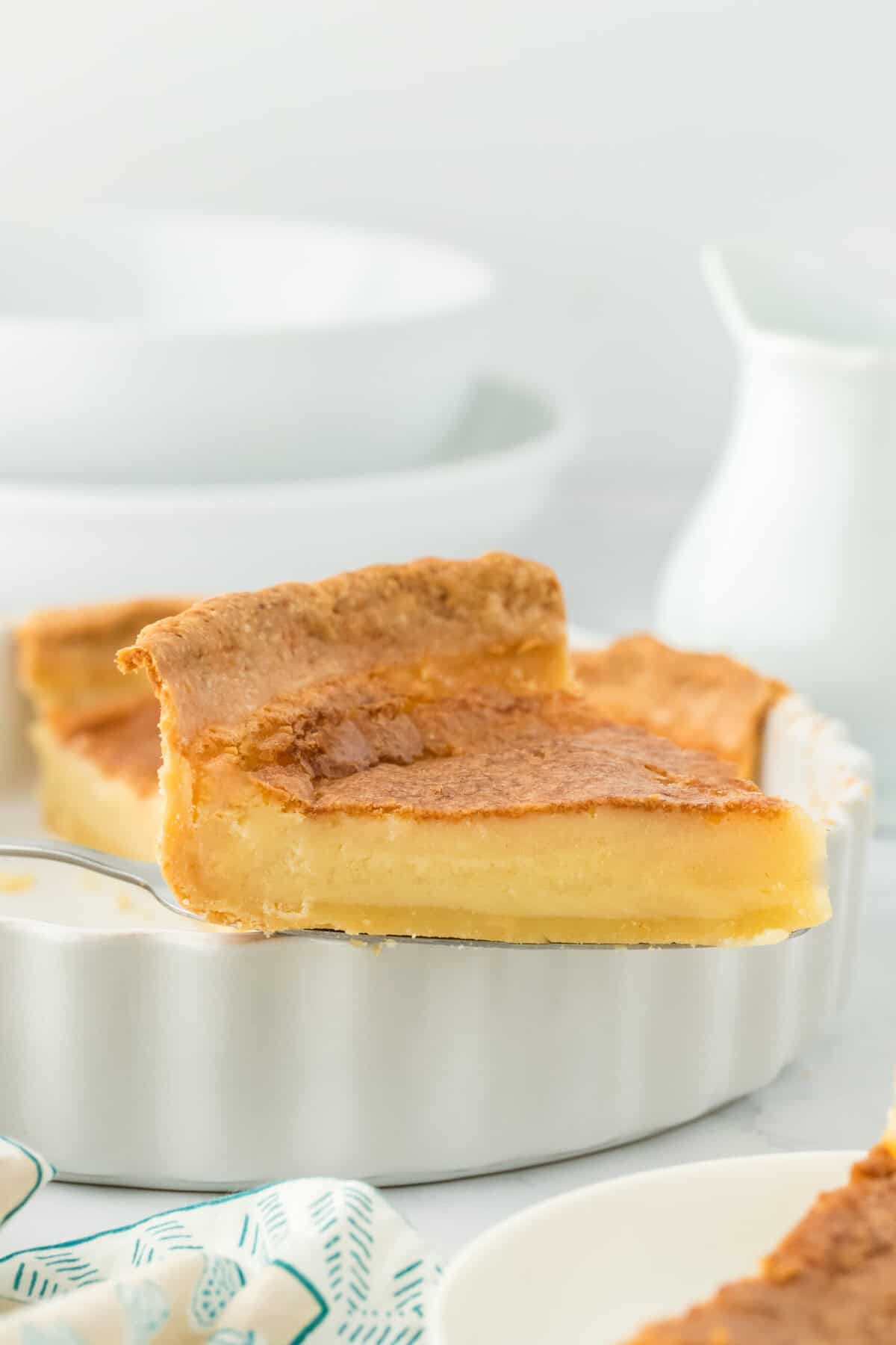 A slice of the best buttermilk pie lifted on a server