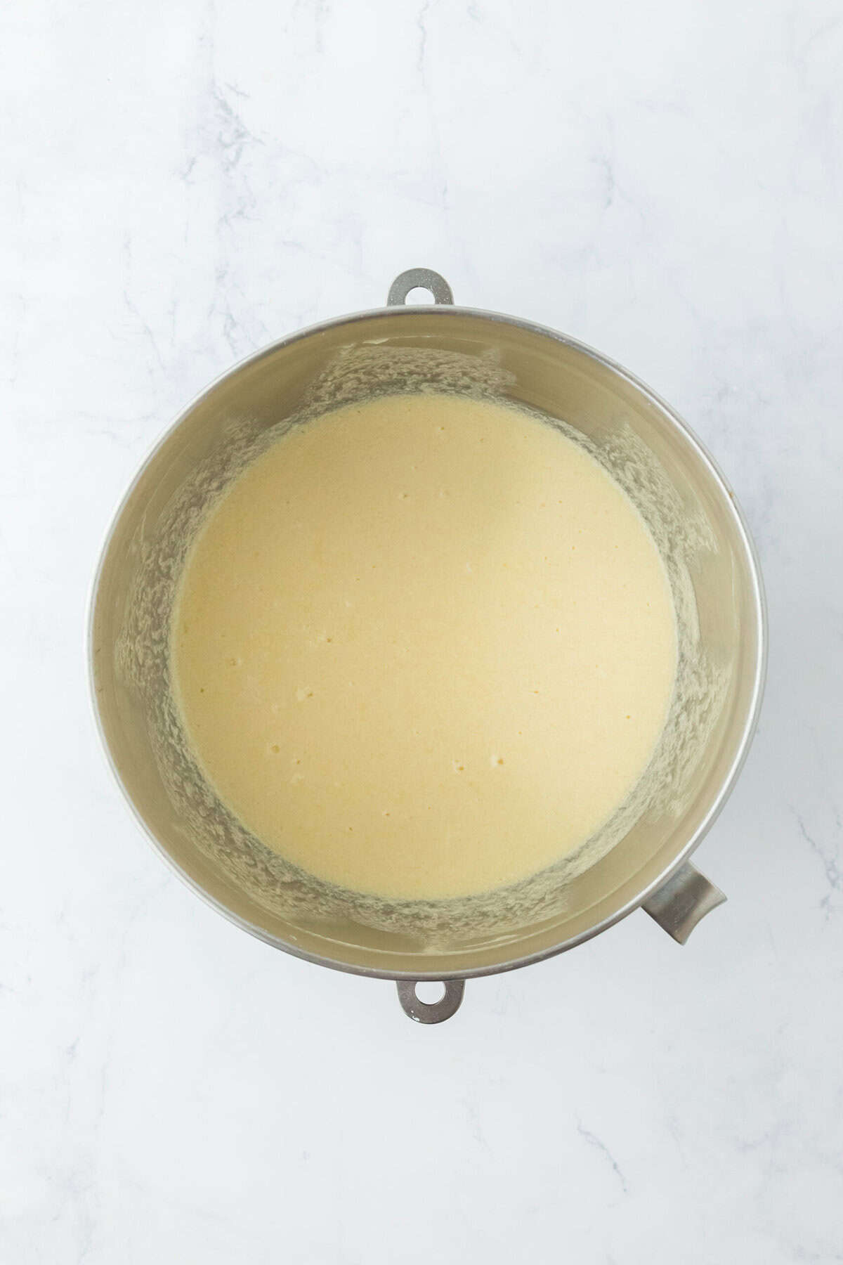 Silky buttermilk pie filling after being mixed in a mixer bowl on white countertop.