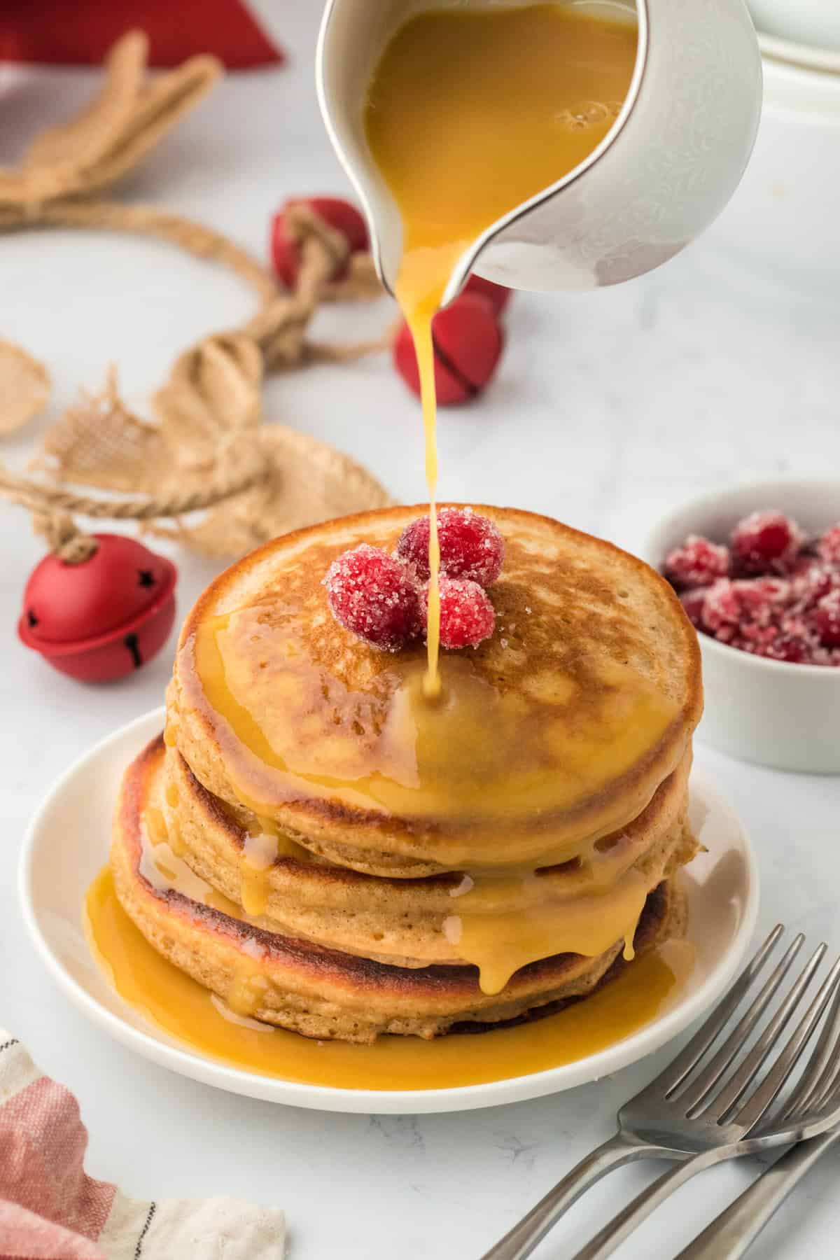 Perfect gingerbread pancakes in a stack on a white plate with syrup being drizzled on top