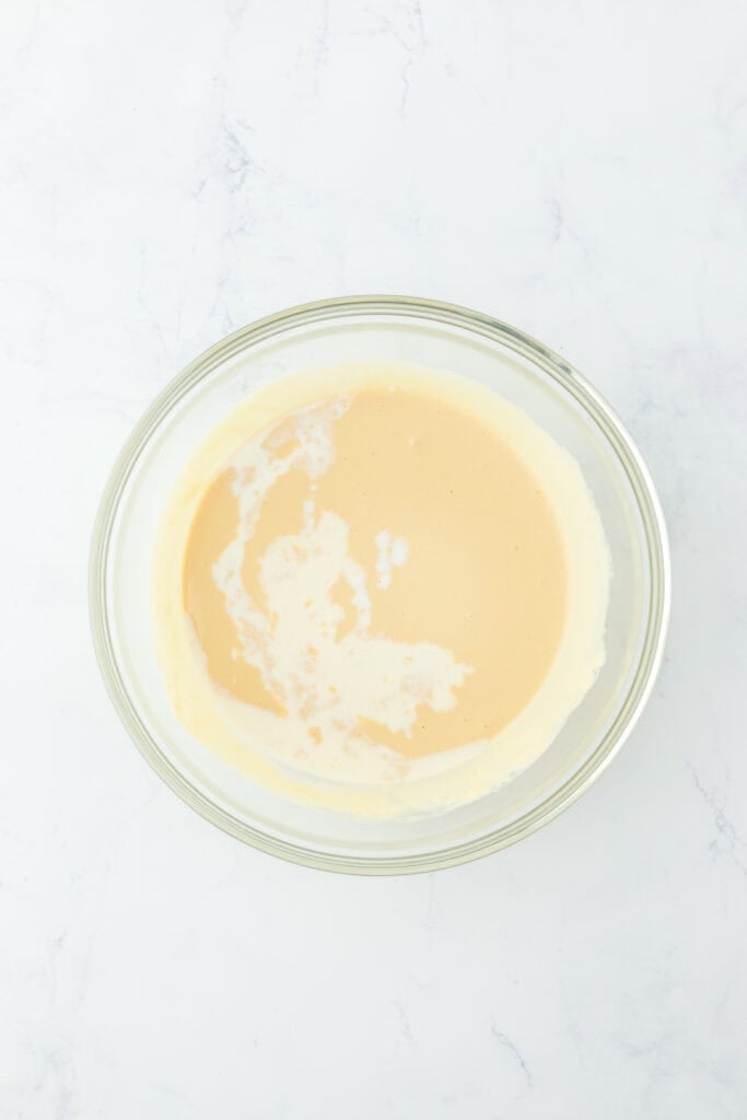 Half and half stirred into gingerbread pancake batter in glass bowl