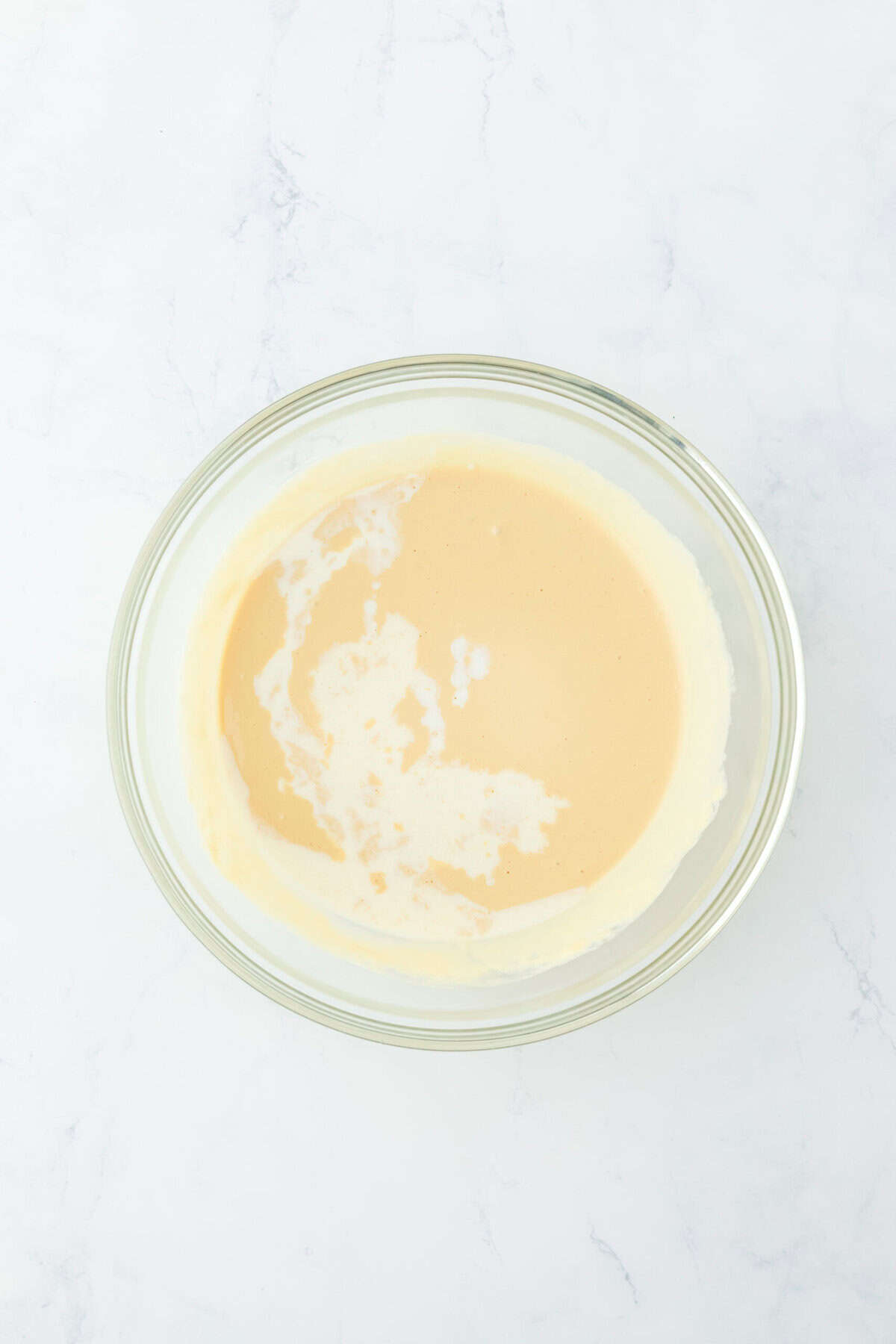 Half and half stirred into gingerbread pancake batter in glass bowl