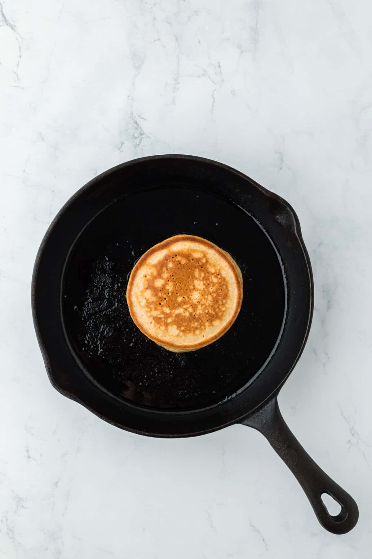 Ginger pancake in a cast iron skillet flipped over.