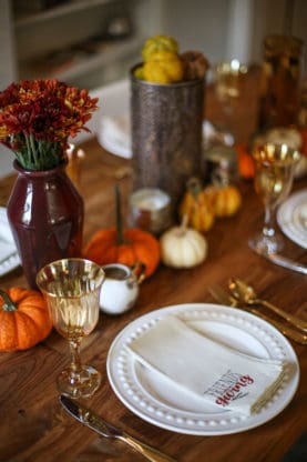 Wood table with dinner rolls and sweet potatoes over celebration tablescape