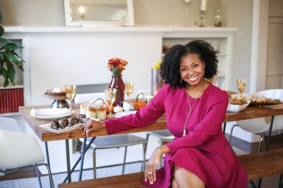 Jocelyn Delk Adams sitting next to Friendsgiving ideas tablescape