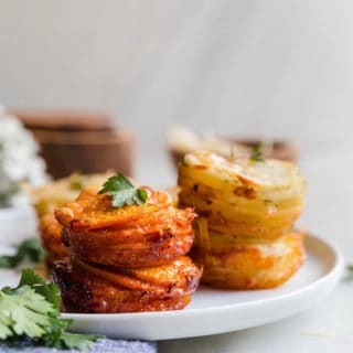 Sweet Potato Stacks and Yukon Gold Potato Stacks on white plate with parsley garnish and white flowers background