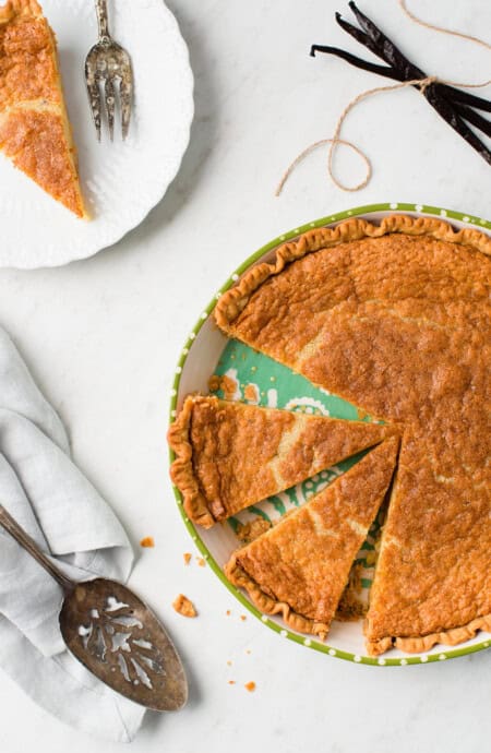 Overhead of Vanilla Buttermilk pie on green pie plate with slice on white dessert plate