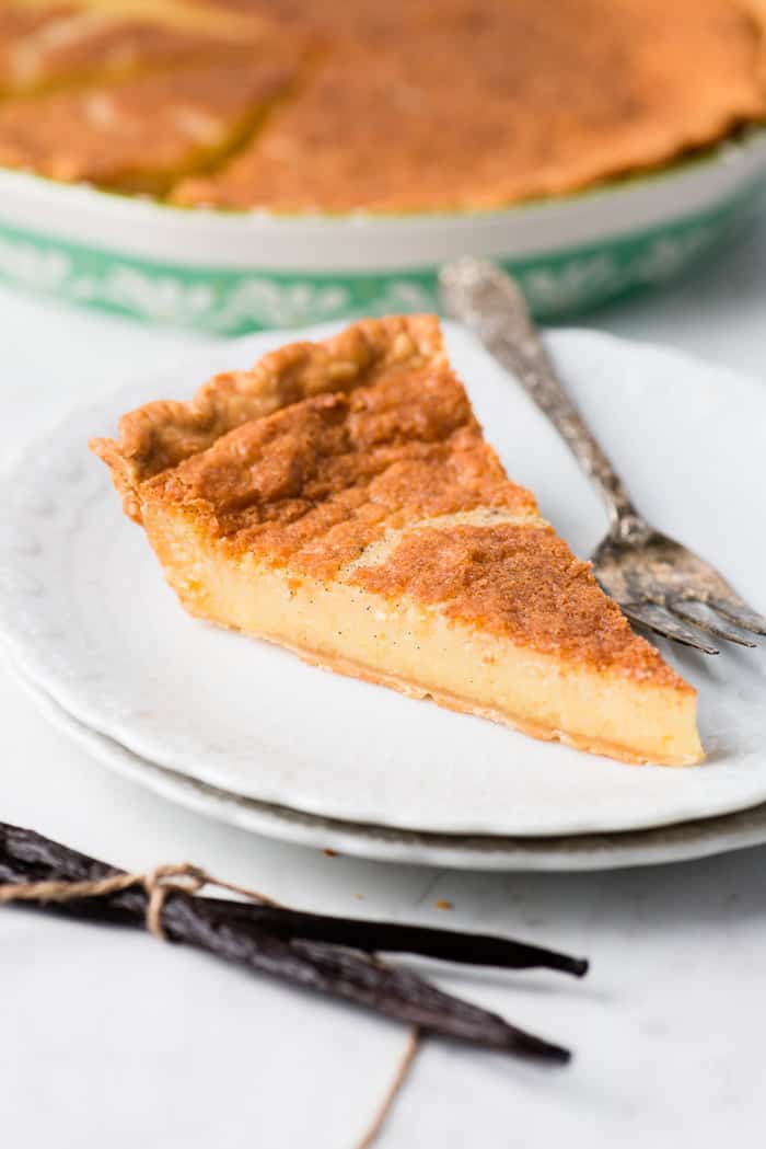 Close up on Vanilla Buttermilk Pie slice on white plate with fork