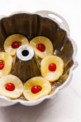 pineapples and cherries lined on bottom of bundt pan for pineapple rum cake