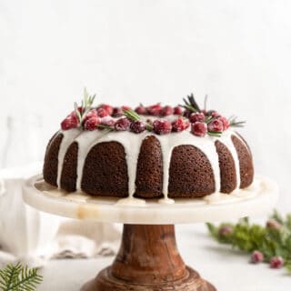 Gingerbread-Cupcakes-and-Gingerbread-Pound-Cake-1 Gingerbread cupcakes and gingerbread pound cake on cake stand against white background with greenery